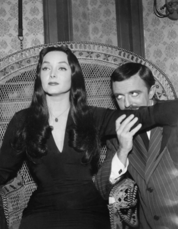 UNITED STATES - APRIL 05: The Addams Family - "Cousin Itt and the Voc. Counselor"- Season One. Gomez ( John Astin) Kisses up Morticia's ( Carolyn Jones) arm as she sits in a large wicker chair., gazing into the distance., (Photo by ABC Photo Archives/ABC via Getty Images)